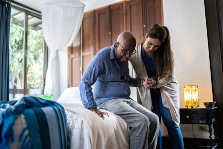 Caregiver assisting man out of bed