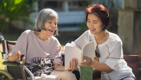 Caregiver reading elderly woman a book
